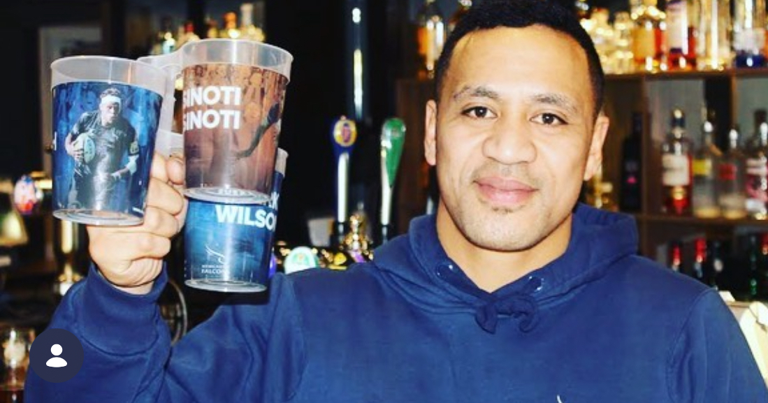 Reusable beer festival cups stacked behind a busy arena bar